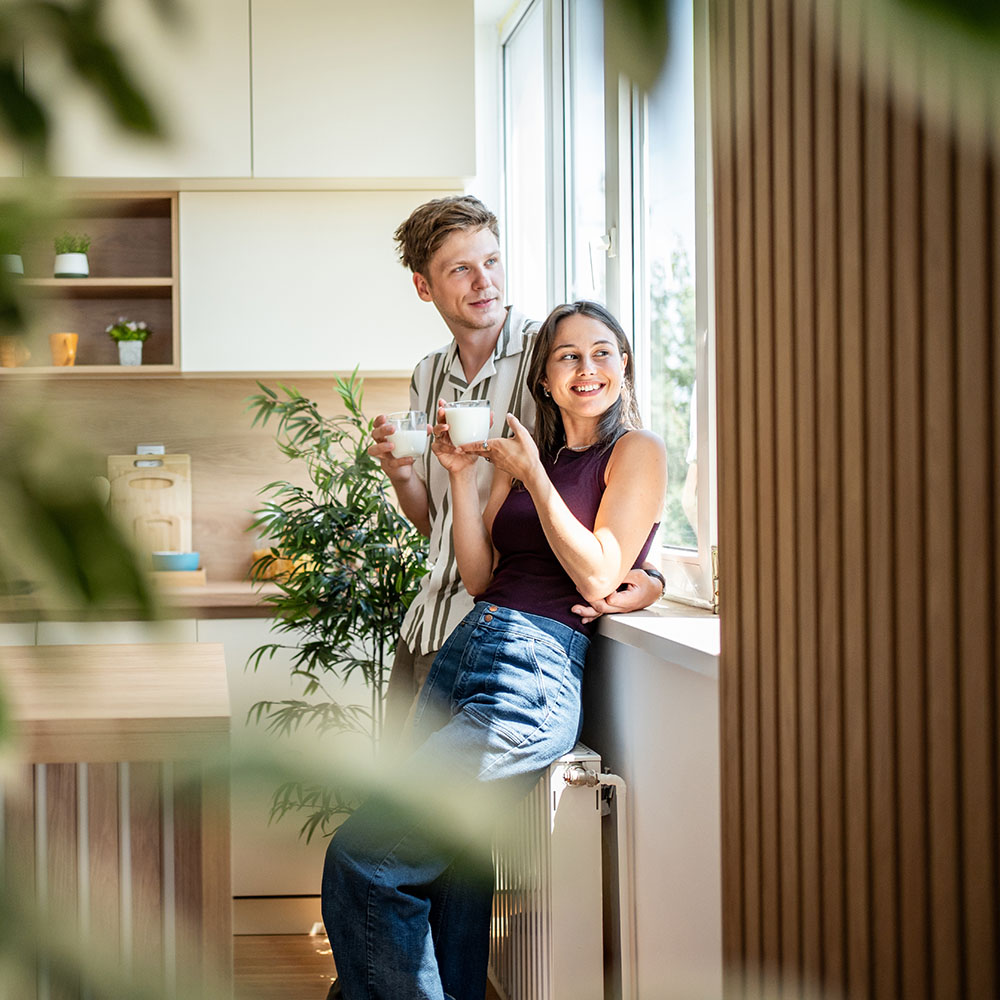 A young couple smiling and drinking coffee in their new home